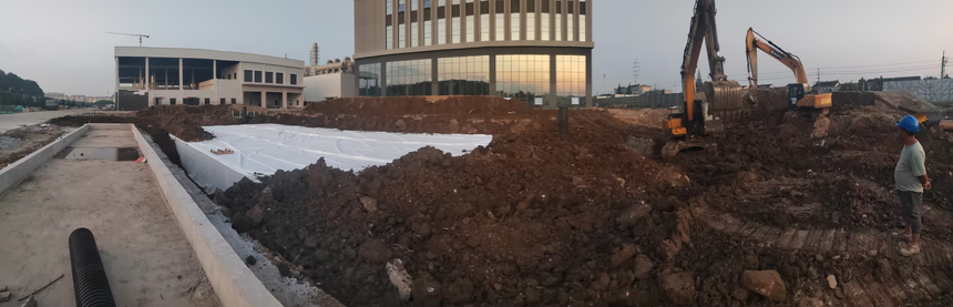 江苏盈源地下雨水调蓄池项目施工现场，大型挖掘机对商业建筑配套蓄水池进行土方回填作业